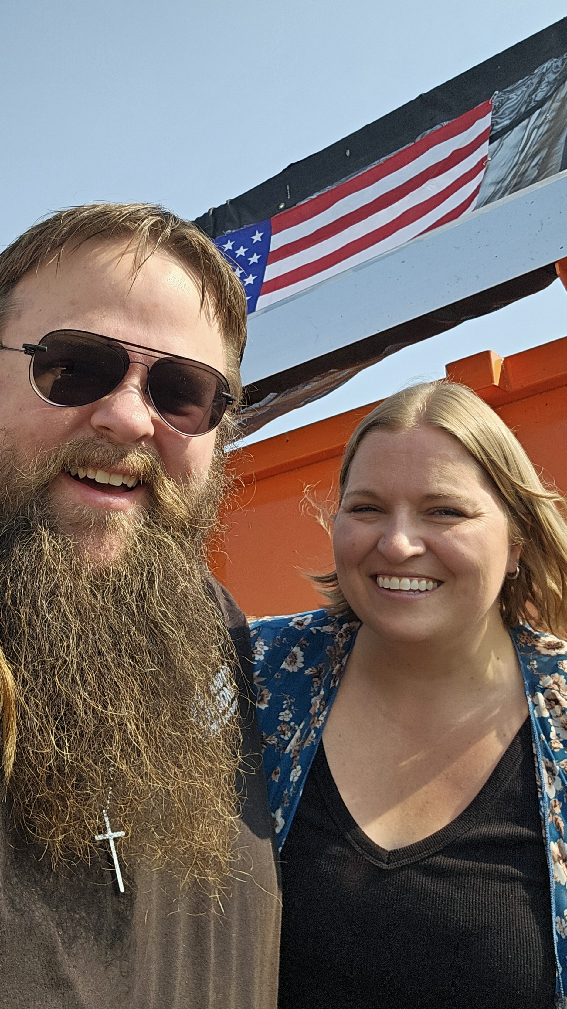 Mark and his wife in front of trailer with American flag